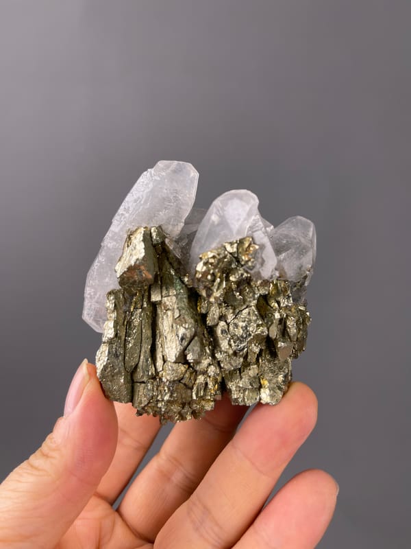 Pyrite specimen featuring brassy crystals beside clear quartz clearly
