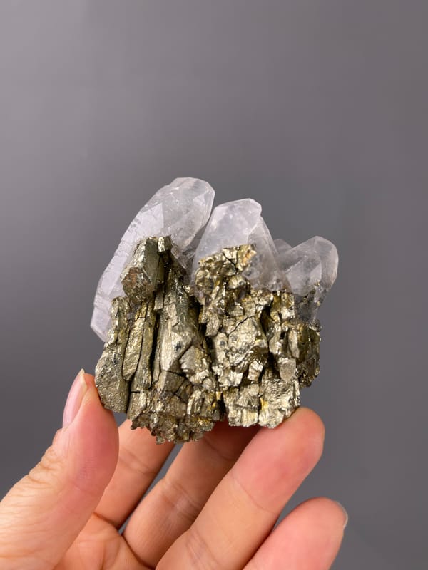 Pyrite specimen showing brassy crystals beside clear quartz distinctly