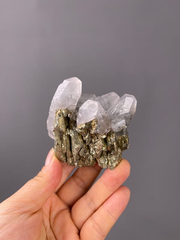 Pyrite specimen displaying brassy crystals beside clear quartz prominently