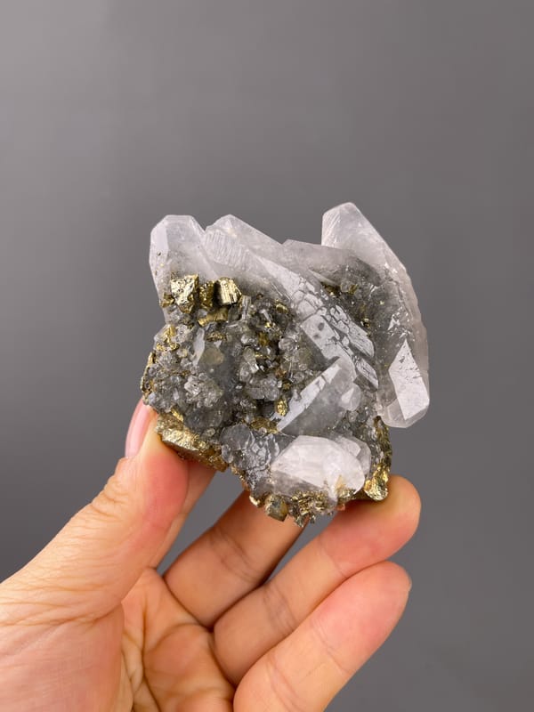 Brassy crystals beside clear quartz seen across this pyrite specimen