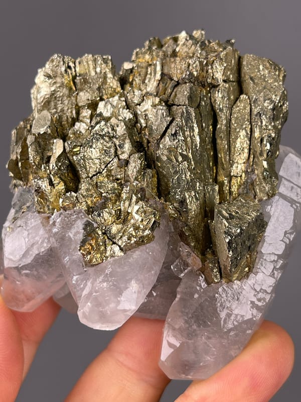 Pyrite specimen bearing brassy crystals beside clear quartz visibly