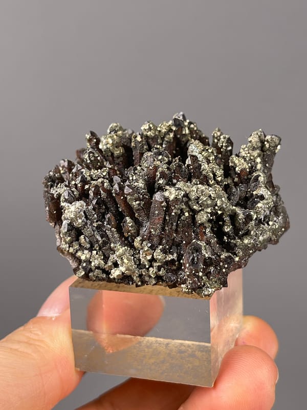 Red quartz specimen from Xianghualing, Hunan, China showing dark quartz prisms with brassy pyrite