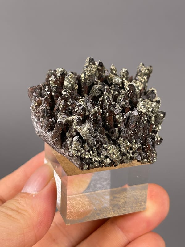 Red quartz specimen from Xianghualing, Hunan, China presenting dark quartz prisms with brassy pyrite