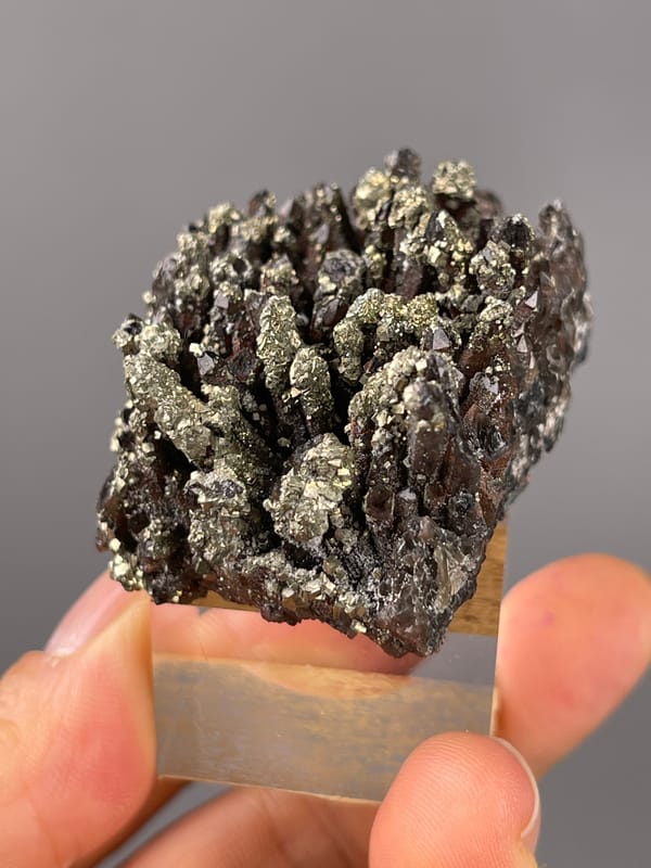Red quartz specimen from Xianghualing, Hunan, China displaying dark quartz prisms with brassy pyrite