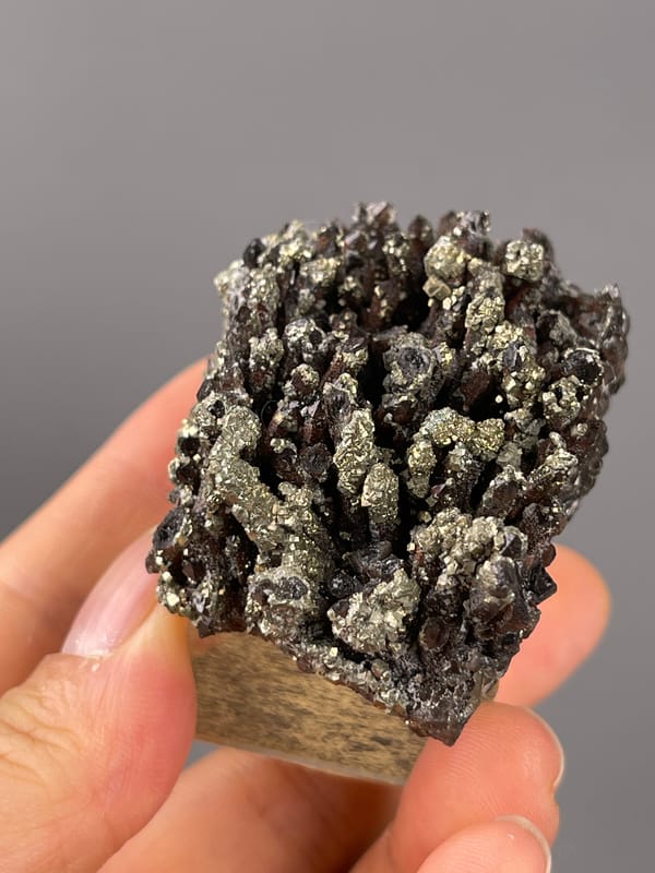 Red quartz specimen from Xianghualing, Hunan, China highlighting dark quartz prisms with brassy pyrite