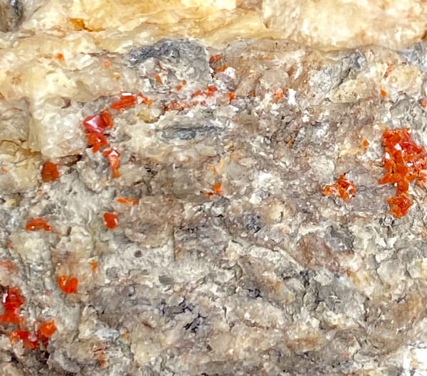 Red wulfenite spots over pale matrix block from Sichuan, China, view 5 of 9