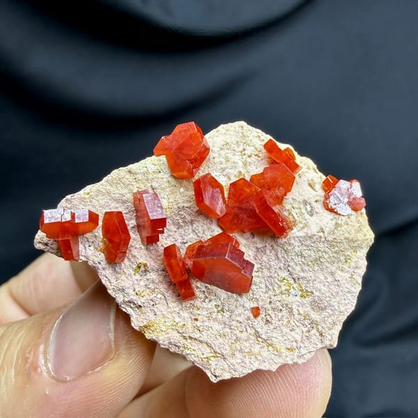 Scarlet vanadinite crystals scattered on pale matrix from Morocco