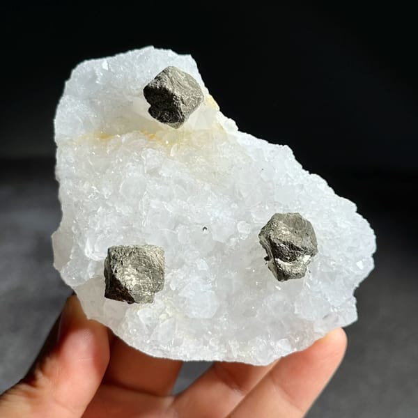 Three ball-shaped pyrite crystals on white quartz plate from Guangxi, China, view 2 of 12