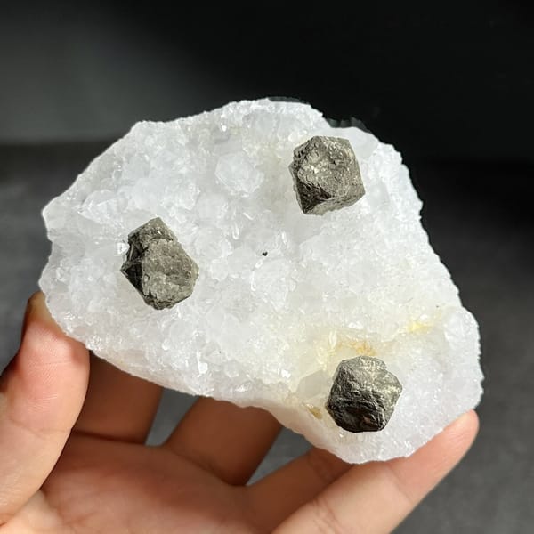 Three ball-shaped pyrite crystals on white quartz plate from Guangxi, China, view 6 of 12