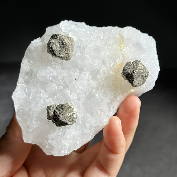 Three ball-shaped pyrite crystals on white quartz plate from Guangxi, China, view 8 of 12