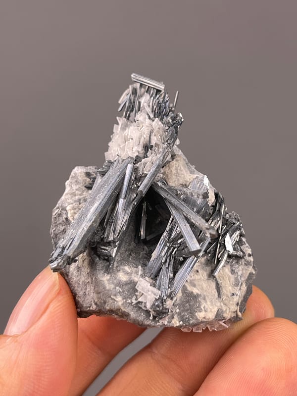 Stibnite with Calcite specimen from Lengshuijiang, Hunan, China featuring steel-gray striated radiating blades