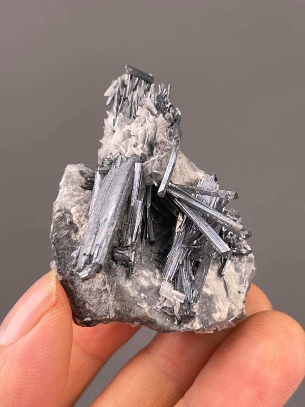 Stibnite with Calcite specimen from Lengshuijiang, Hunan, China showing steel-gray striated radiating blades