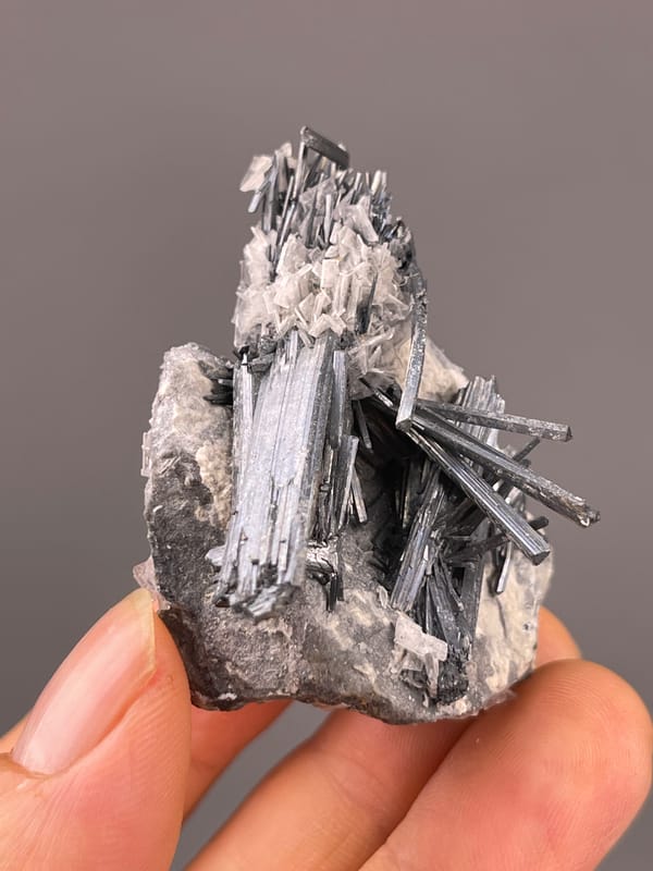 Stibnite with Calcite specimen from Lengshuijiang, Hunan, China presenting steel-gray striated radiating blades