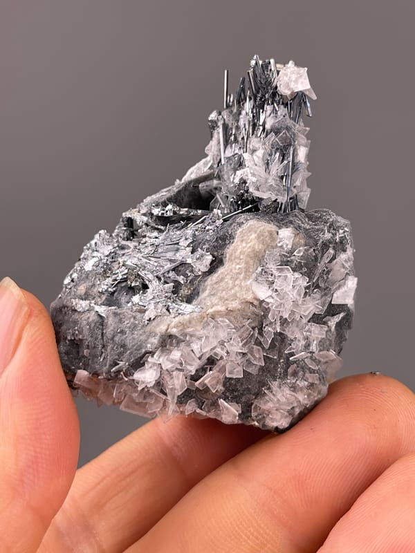 Stibnite with Calcite specimen from Lengshuijiang, Hunan, China highlighting steel-gray striated radiating blades