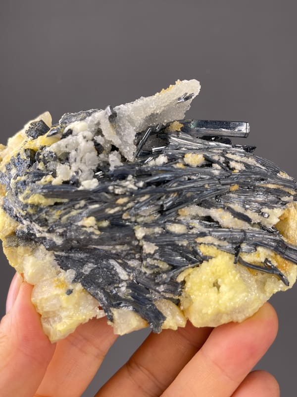 Steel-gray blades with pale crystals visible on stibnite specimen from Lengshuijiang, Hunan, China