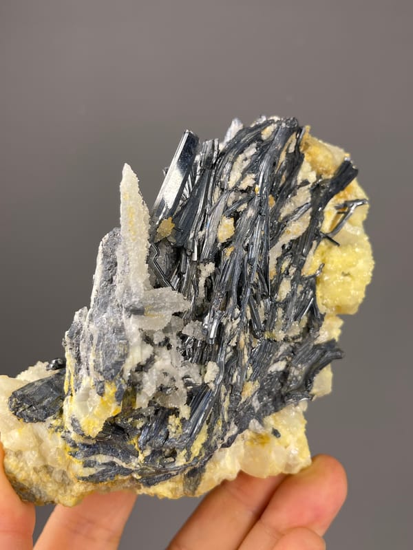Stibnite specimen from Lengshuijiang, Hunan, China displaying steel-gray blades with pale crystals
