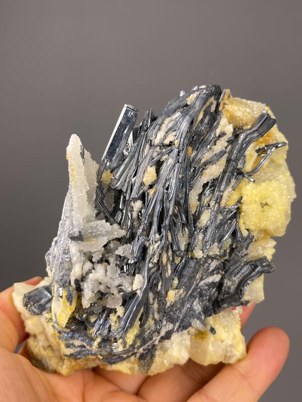 Stibnite specimen from Lengshuijiang, Hunan, China highlighting steel-gray blades with pale crystals