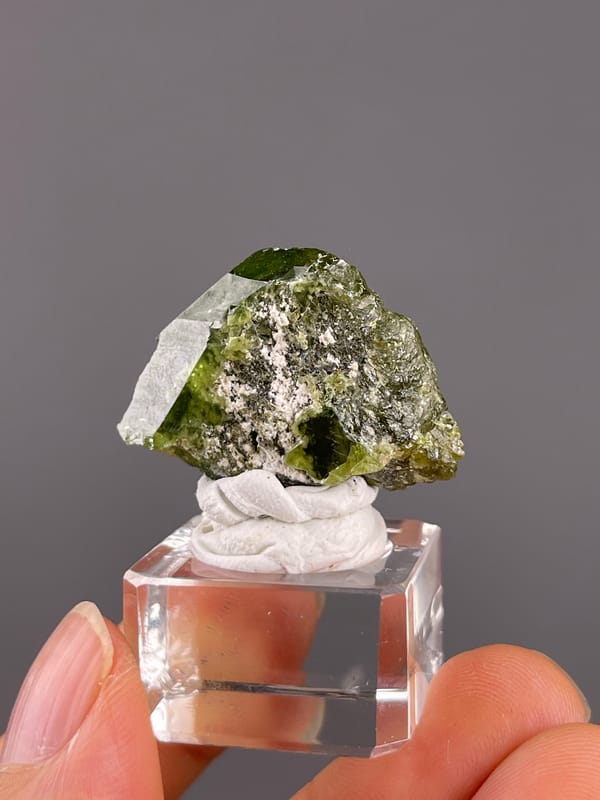 Tourmaline from Brazil: compact green crystal with pale granular material across its face.