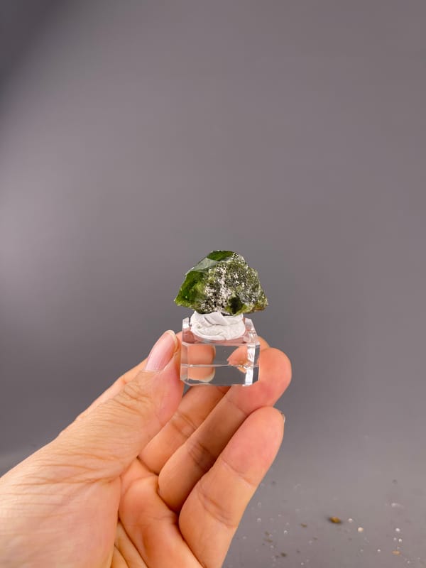 Tourmaline from Brazil: whole compact crystal on a clear cube held at a distance.