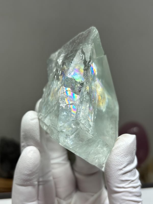 Transparent pale fluorite with rainbow flash from Xuebaoding, Sichuan, China, held in gloved hand