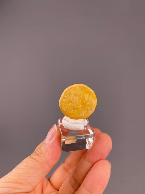 Unidentified specimen from China: whole yellow disc on its clear display cube.