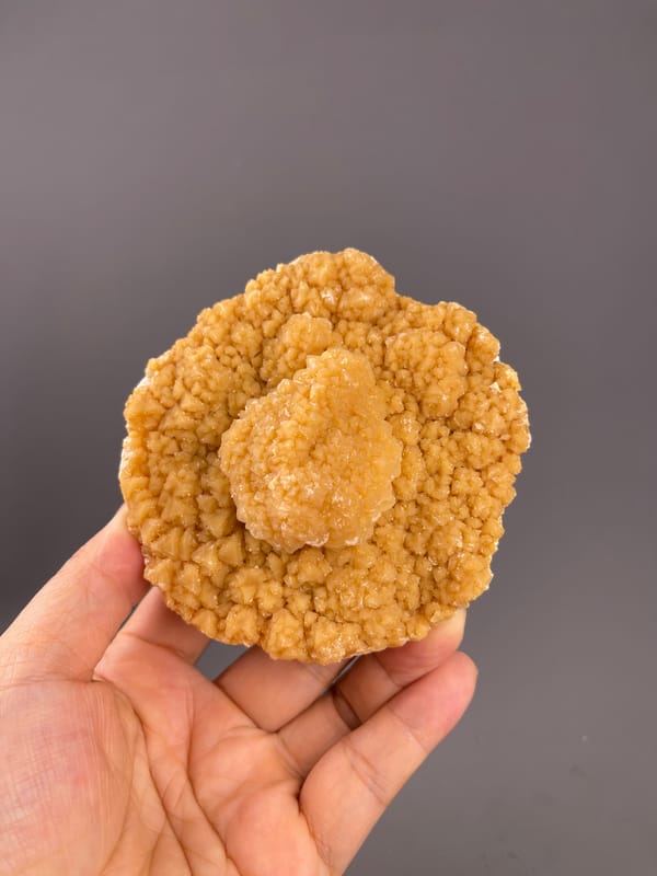 Unidentified specimen from Yunnan, China: rounded golden cluster resting across the fingers.
