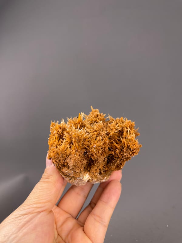 Unidentified specimen from Yunnan, China: whole orange brown cluster held above the fingers.