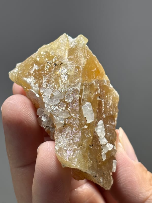 Unusual honey scheelite floater with calcite from Xuebaoding, Sichuan, China, held in hand