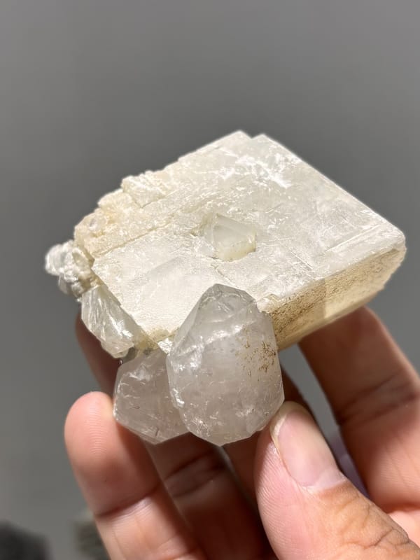 White calcite block with clear quartz crystal from Xuebaoding, Sichuan, China, held in hand