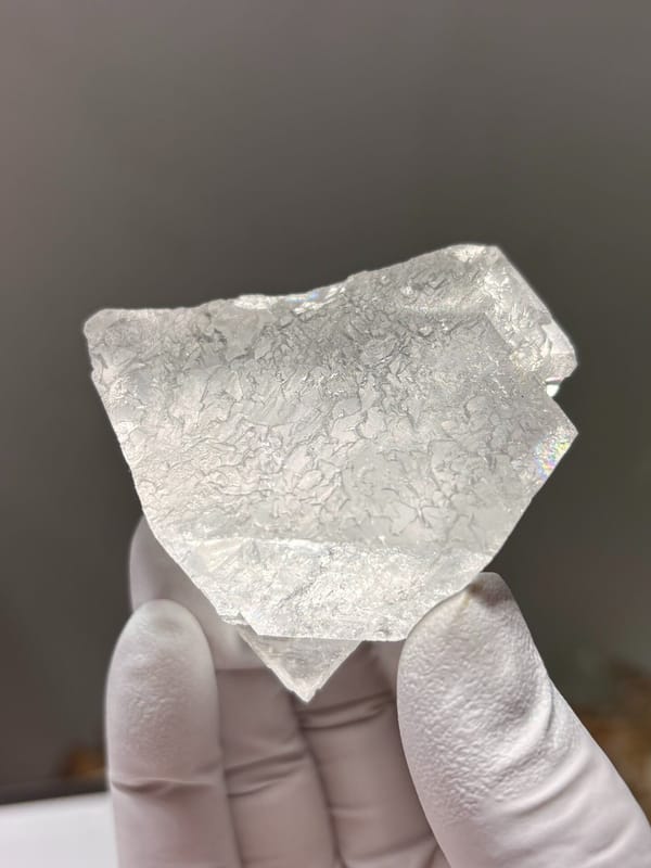 White fluorite octahedron with lace-like pattern from Xuebaoding, Sichuan, China, held in gloved hand