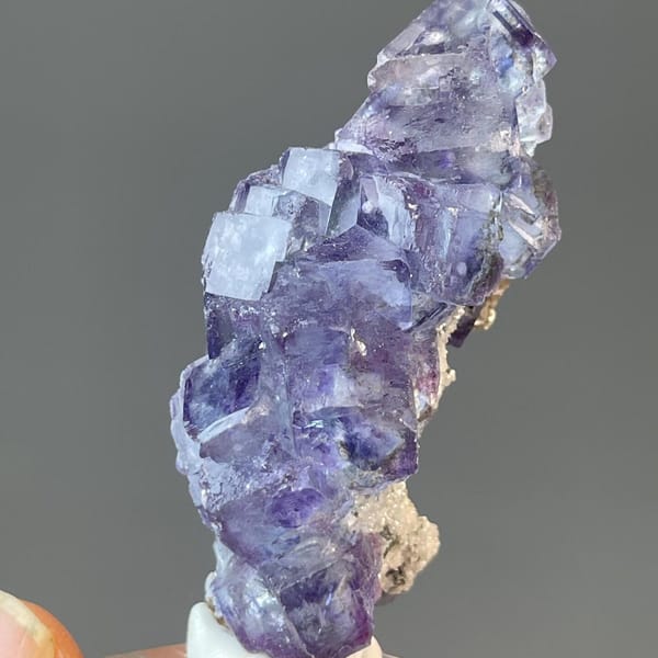 Miniature twinned fluorite held in the hand for scale