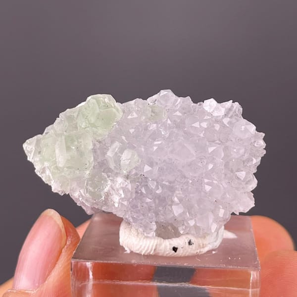 Toenail-size green fluorite with quartz held in the hand